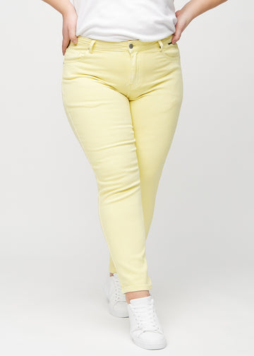 Slim jeans for women in light yellow, color Lemonades. Front view on a plus-size model, showing a close fit through the leg with a little more room at the ankle.