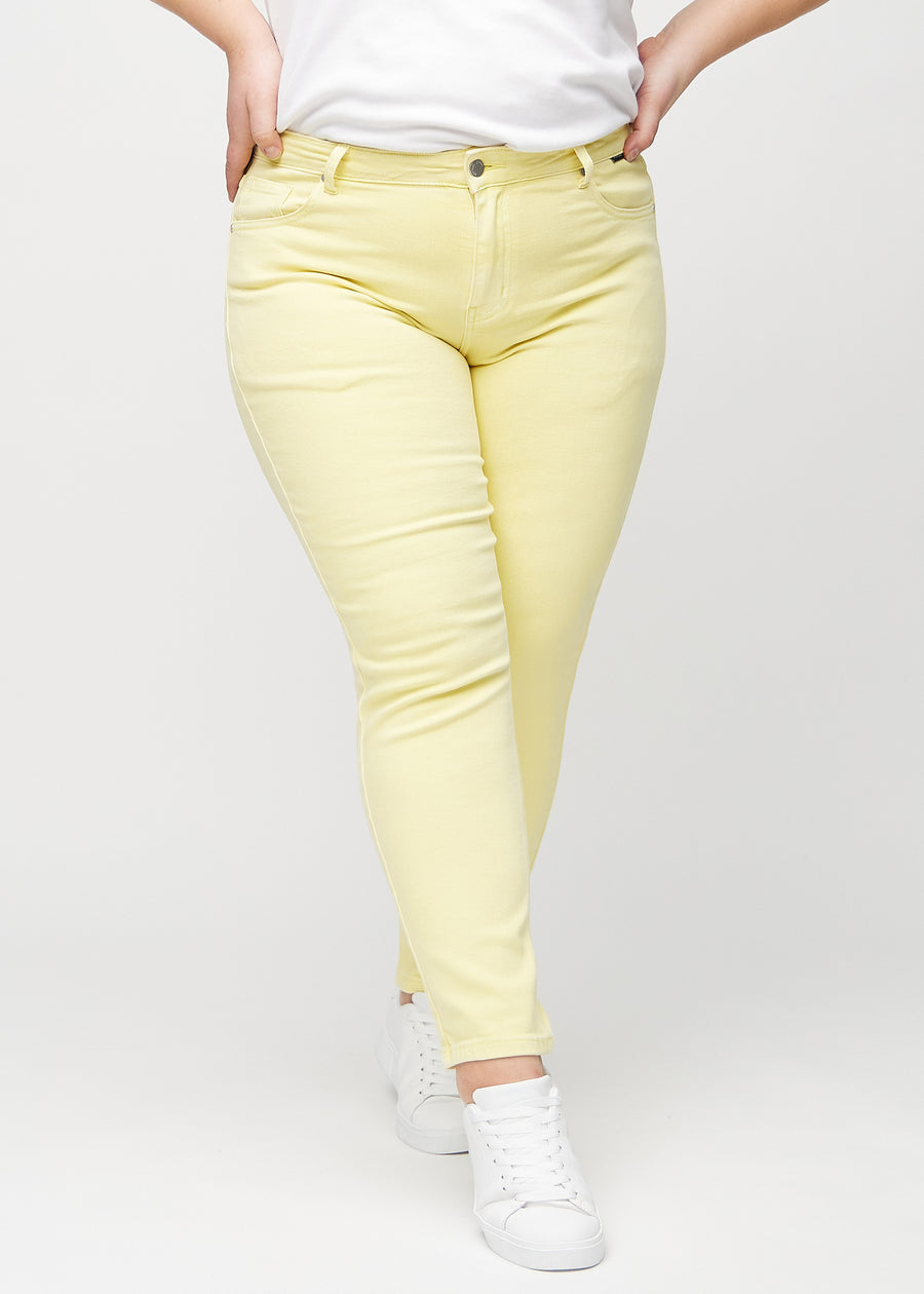 Slim jeans for women in light yellow, color Lemonades. Front view on a plus-size model, showing a close fit through the leg with a little more room at the ankle.