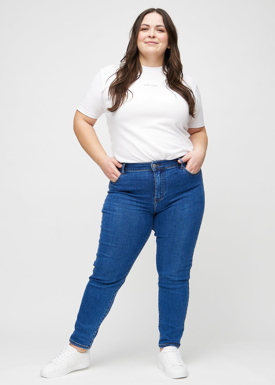 Slim jeans for women in dark blue, color Oceans. Full-length view of a plus-size model wearing the jeans.