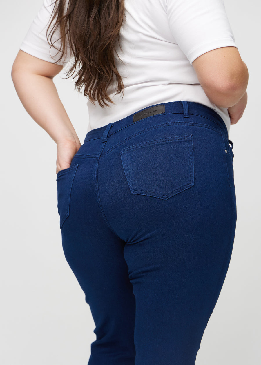 Slim jeans for women in dark blue, color Royals. Close-up back view on a plus-size model, showing the details.