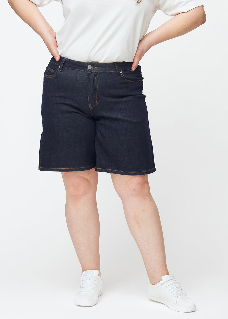 Deep dark blue denim shorts for women in the colour Midnights with a loose fit seen from the front on a plus-size model.