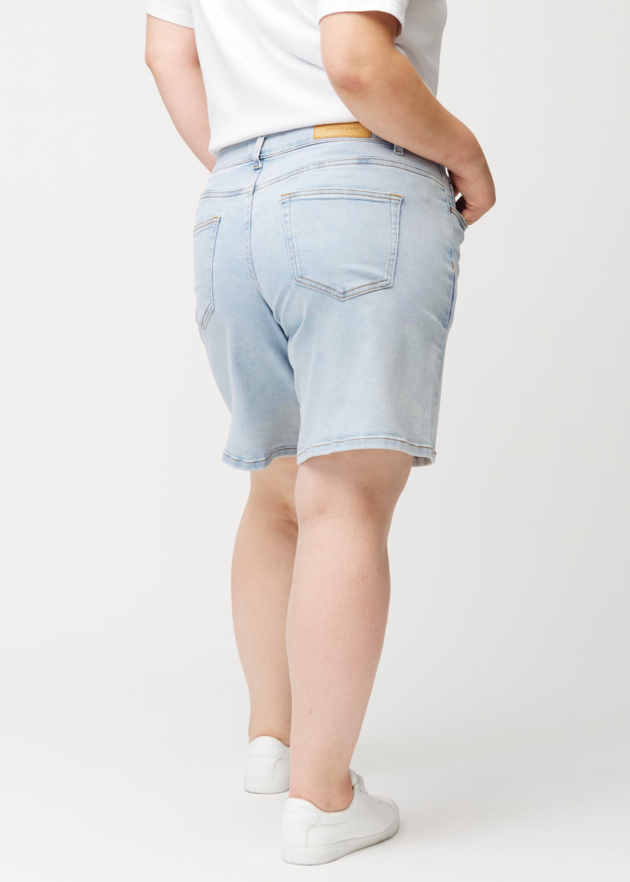 Back view of a female model wearing light blue Waves denim shorts.