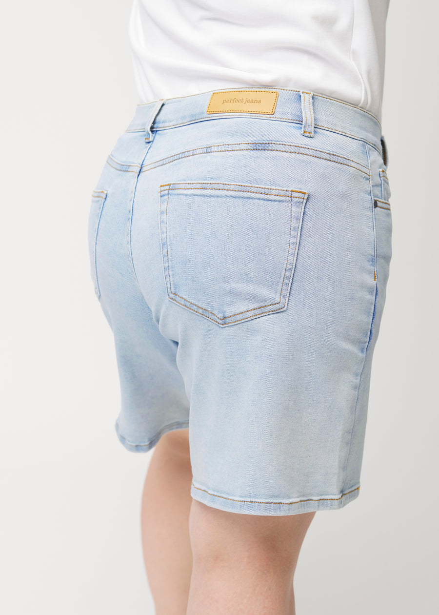 Close-up back view of a female model wearing light blue Waves denim shorts.
