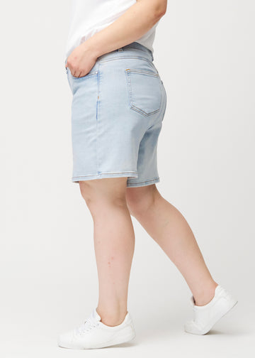 Side view of a female model wearing light blue Waves denim shorts with a mid-rise waist and loose fit.