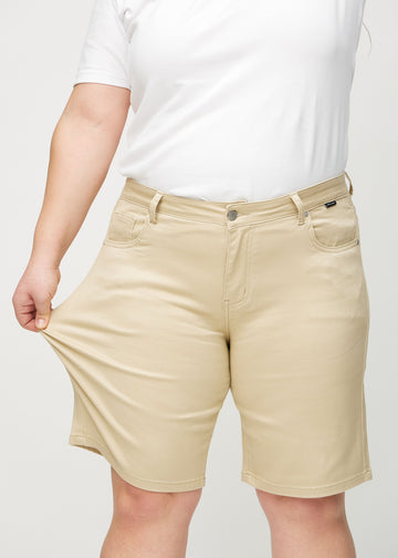 The plus-size model stretches the shorts at the thigh to show the stretch.
