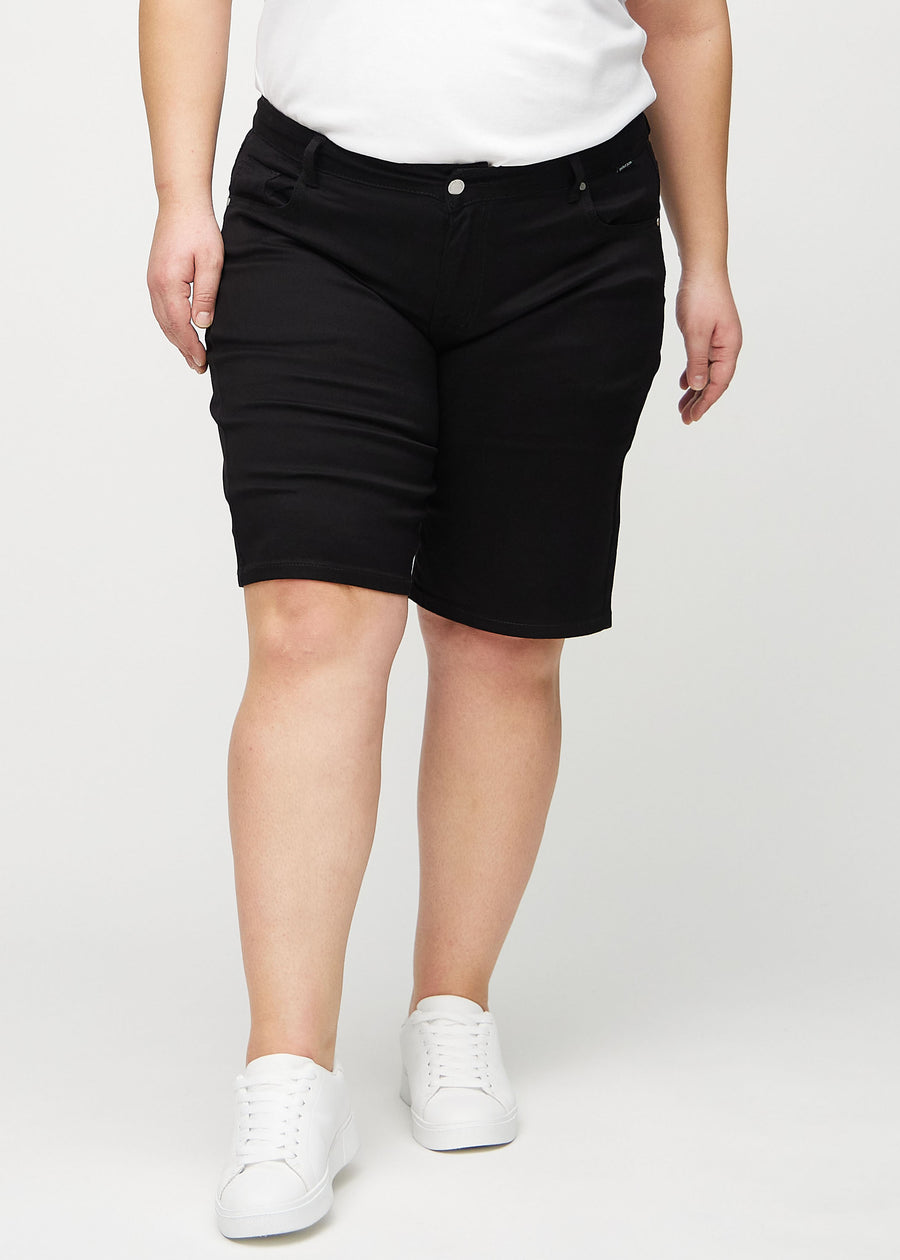 Black regular middle shorts, model name Ravens, which go straight down the leg and end just above the knee on a plus-size model, seen from the front.
