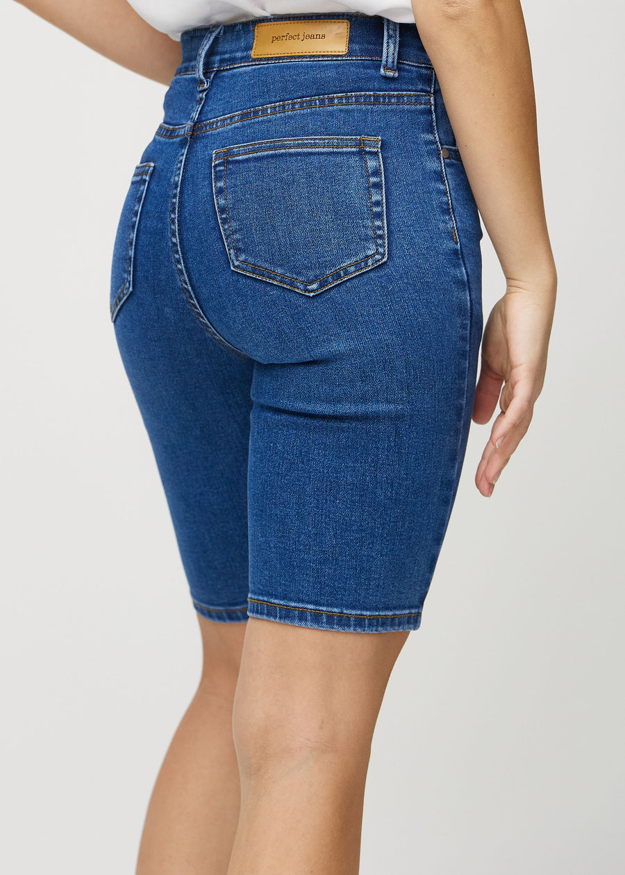 Dark denim skinny middle shorts seen from the back close up to show details.