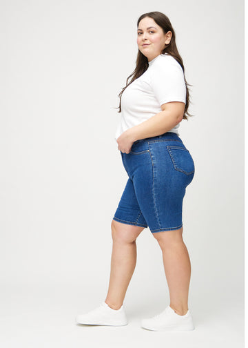 Dark denim skinny middle shorts seen from the side on a plus-size model.