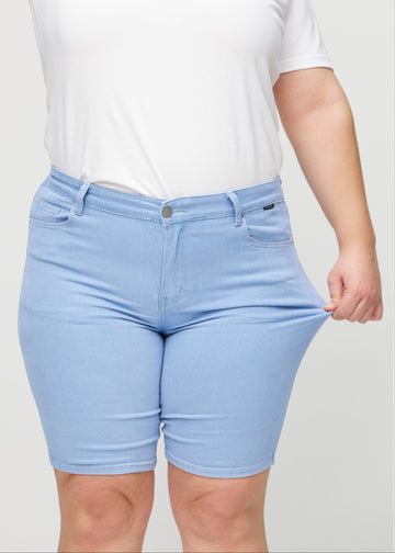The plus-size model stretches the shorts at the thigh to show the stretch.