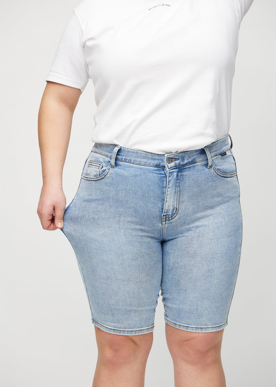 The plus-size model stretches the shorts at the thigh to show the stretch.