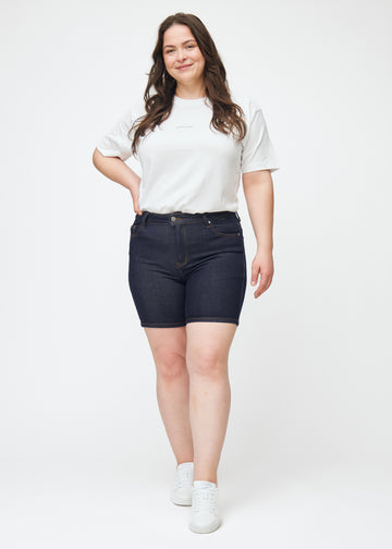 Full image of a plus-size model wearing deep dark blue denim shorts for women in the colour Midnights with a skinny fit.