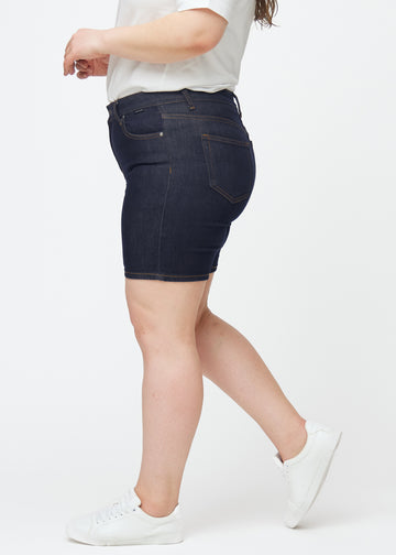 Deep dark blue denim shorts for women in the colour Midnights with a skinny fit seen from the side on a plus-size model.