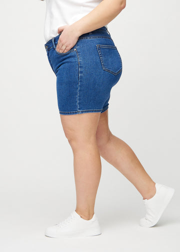 Dark denim skinny short shorts seen from the side on a plus-size model.