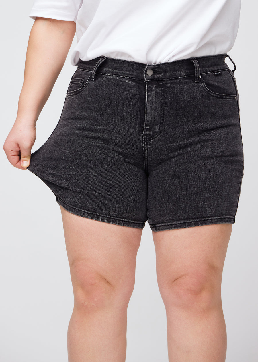 Plus-size model stretches the shorts at the thigh to show the stretch.