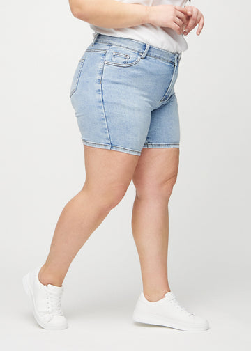 Light denim skinny short shorts seen from the side on a plus-size model.
