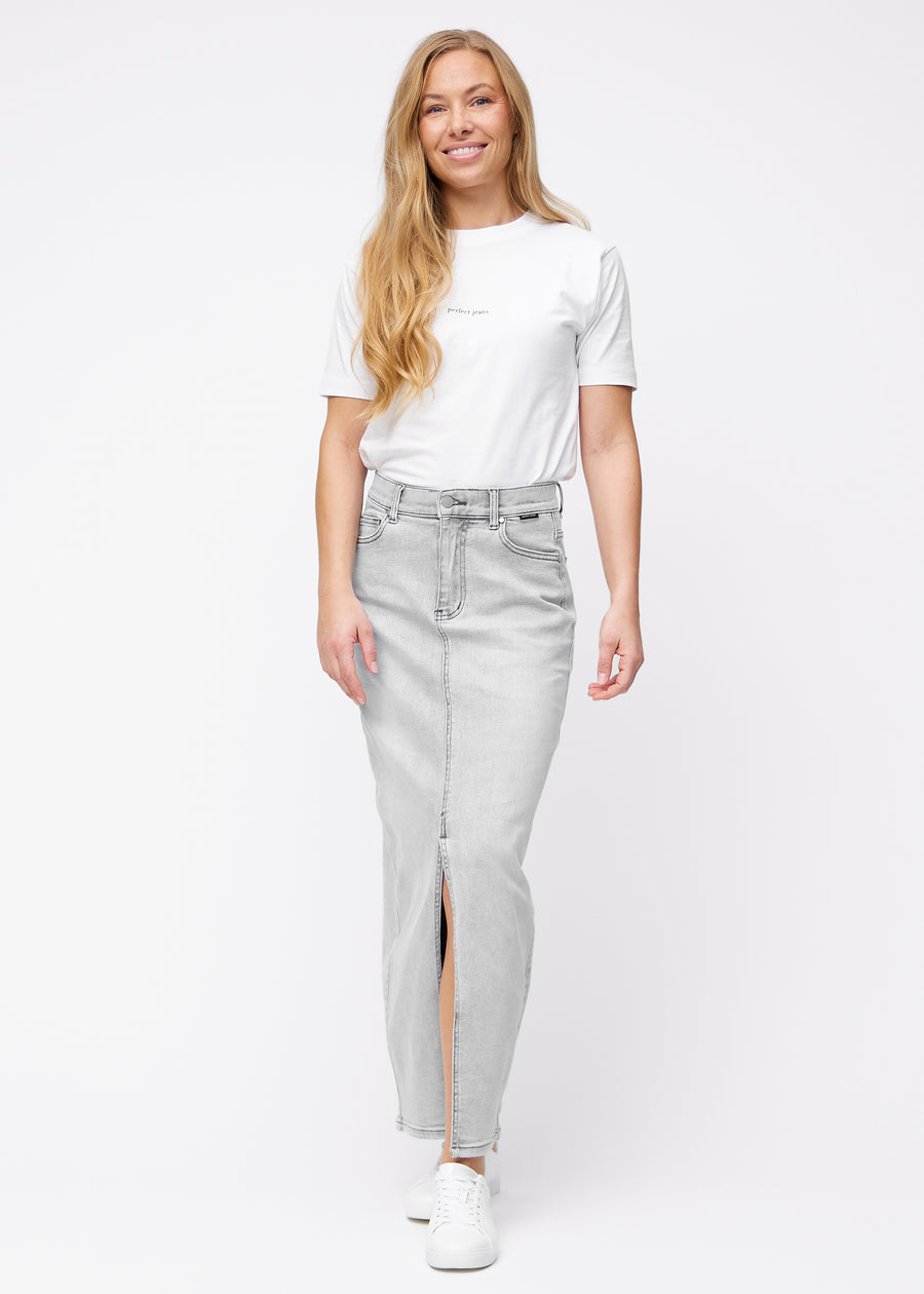 Long light grey denim skirt for women in the color Ashes. Full-length view of a model wearing the skirt with a front slit.