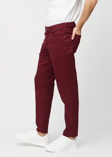 Dark red regular jeans seen from the side on a model.
