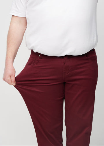 The plus-size model stretches the jeans at the thigh to show the stretch.