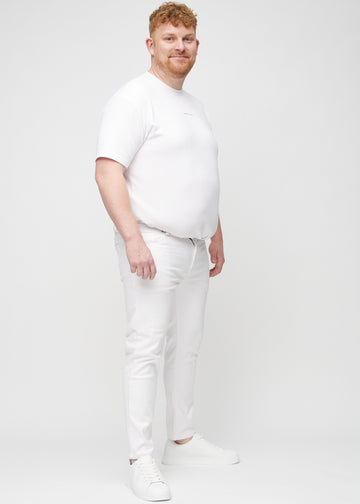 Full-length view of a plus-size model in white slim jeans.