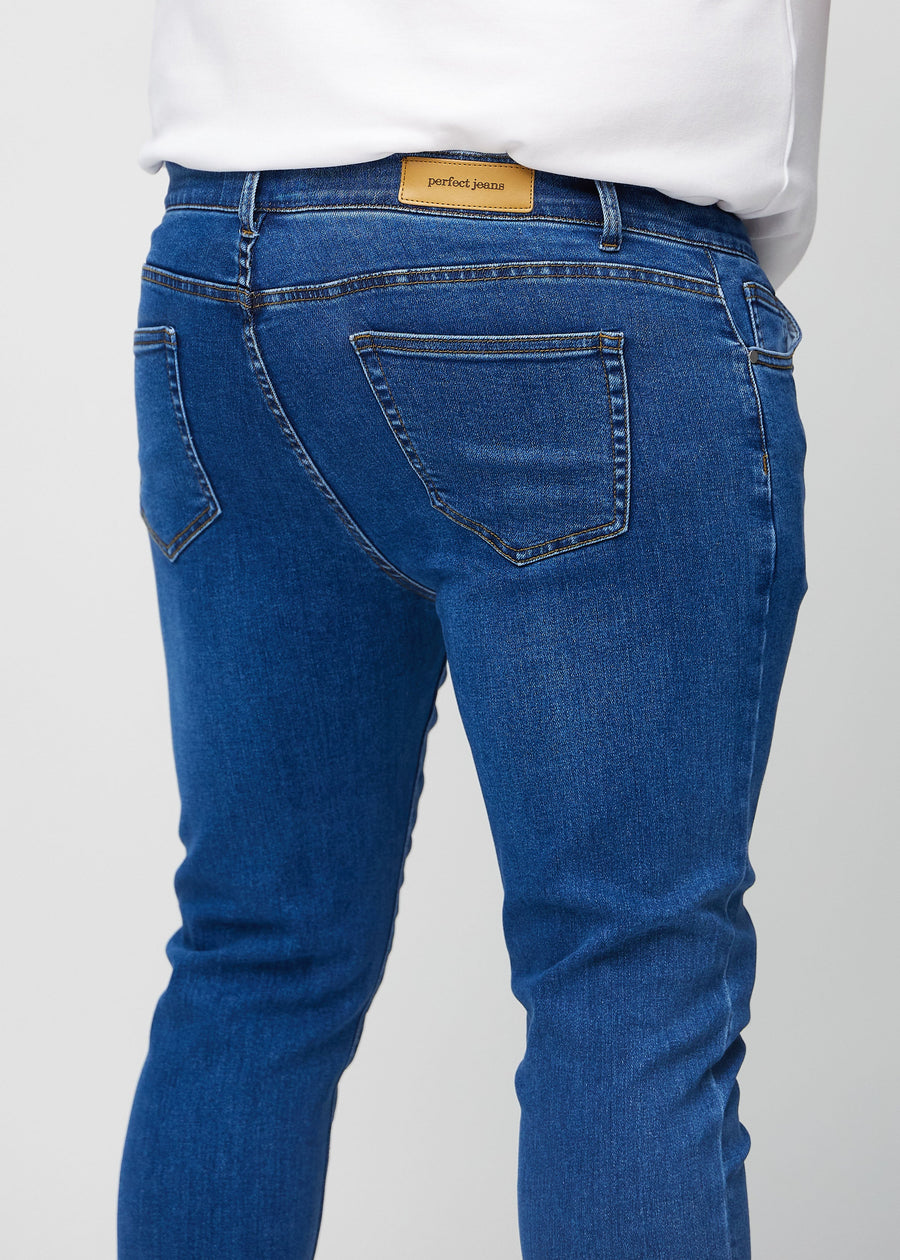Close-up back view of dark blue denim slim jeans on a plus-size model showing details.
