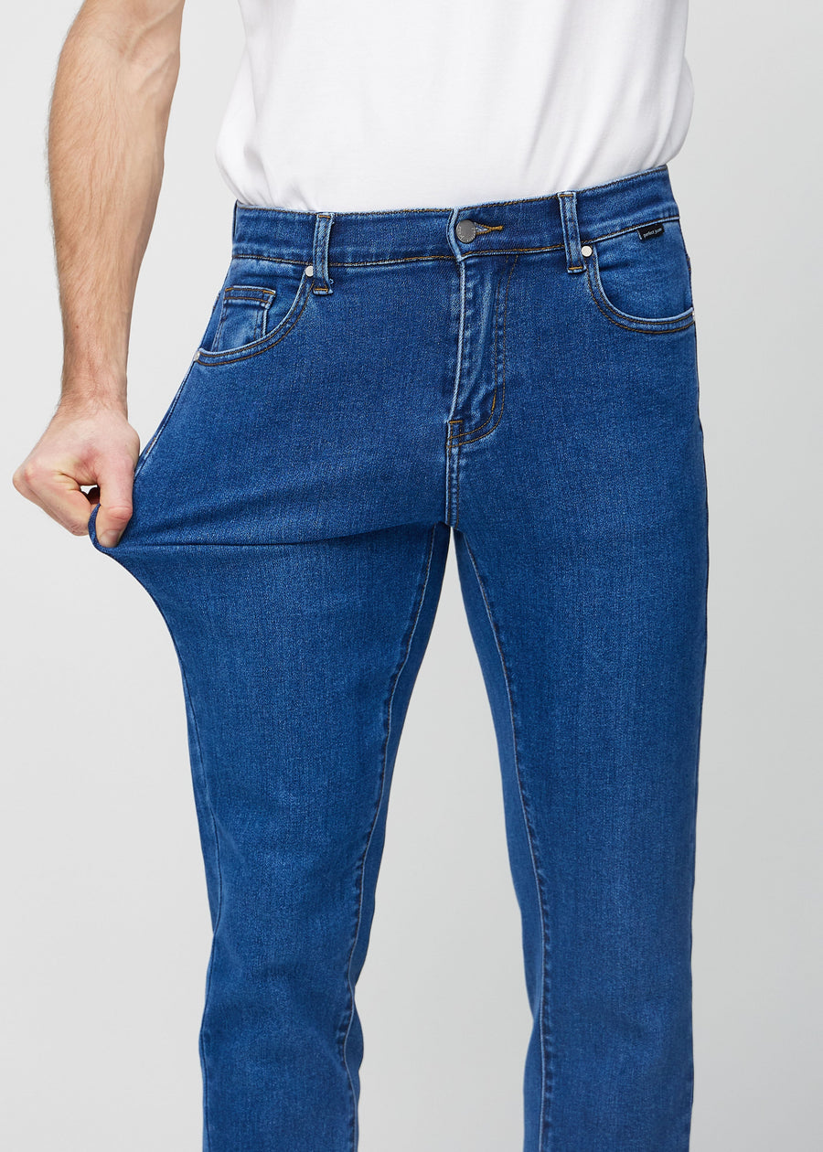 Model stretches the jeans at the thigh to show the fabric&