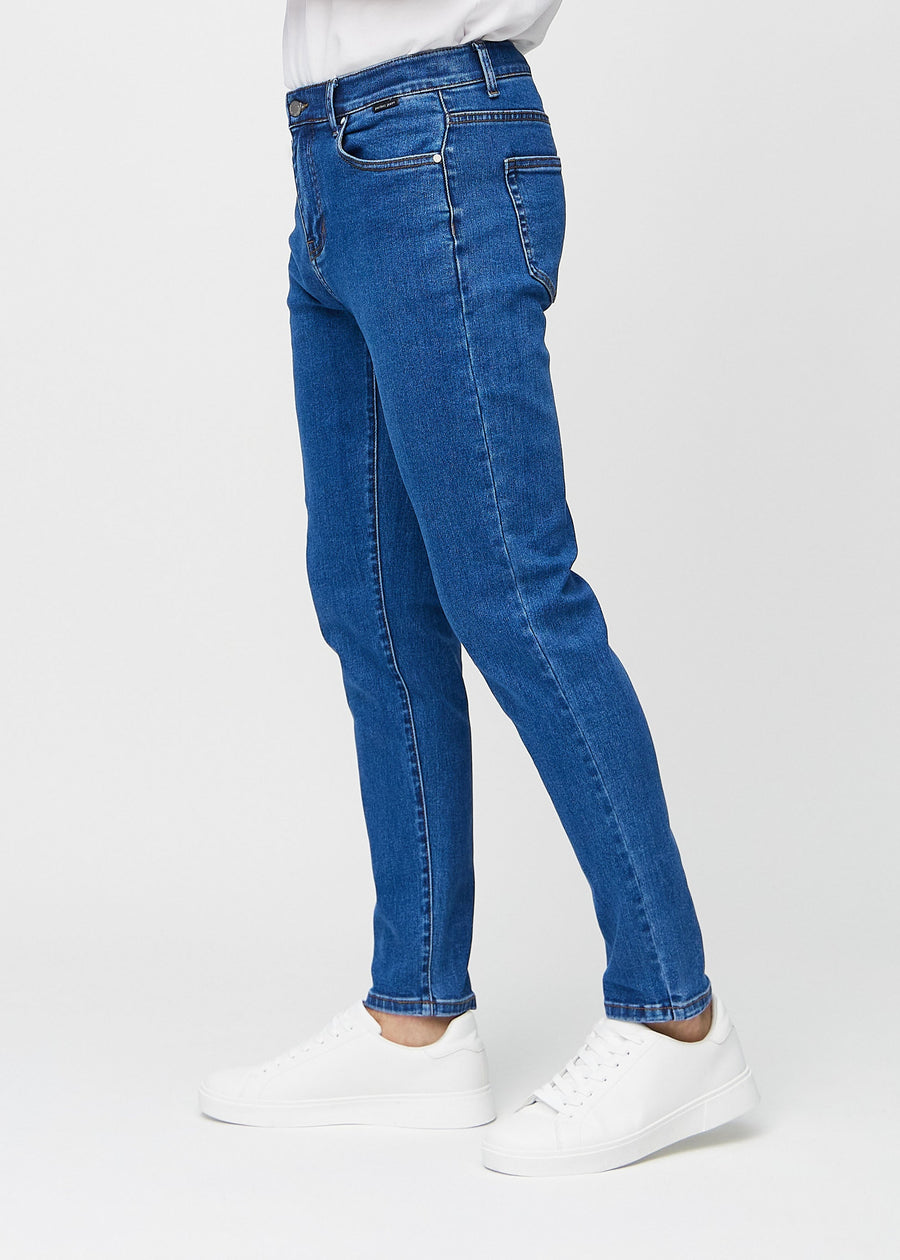 Dark blue denim slim jeans viewed from the side on a model.