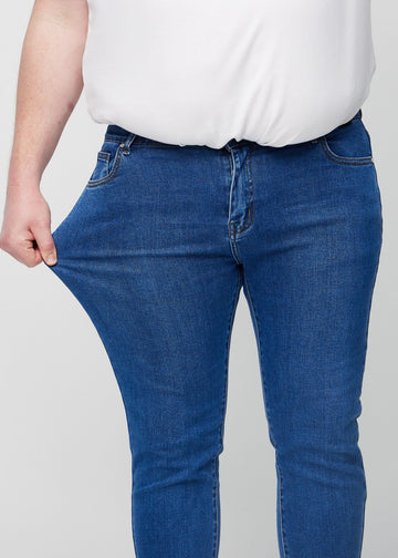 Plus-size model stretches the jeans at the thigh to show the fabric&