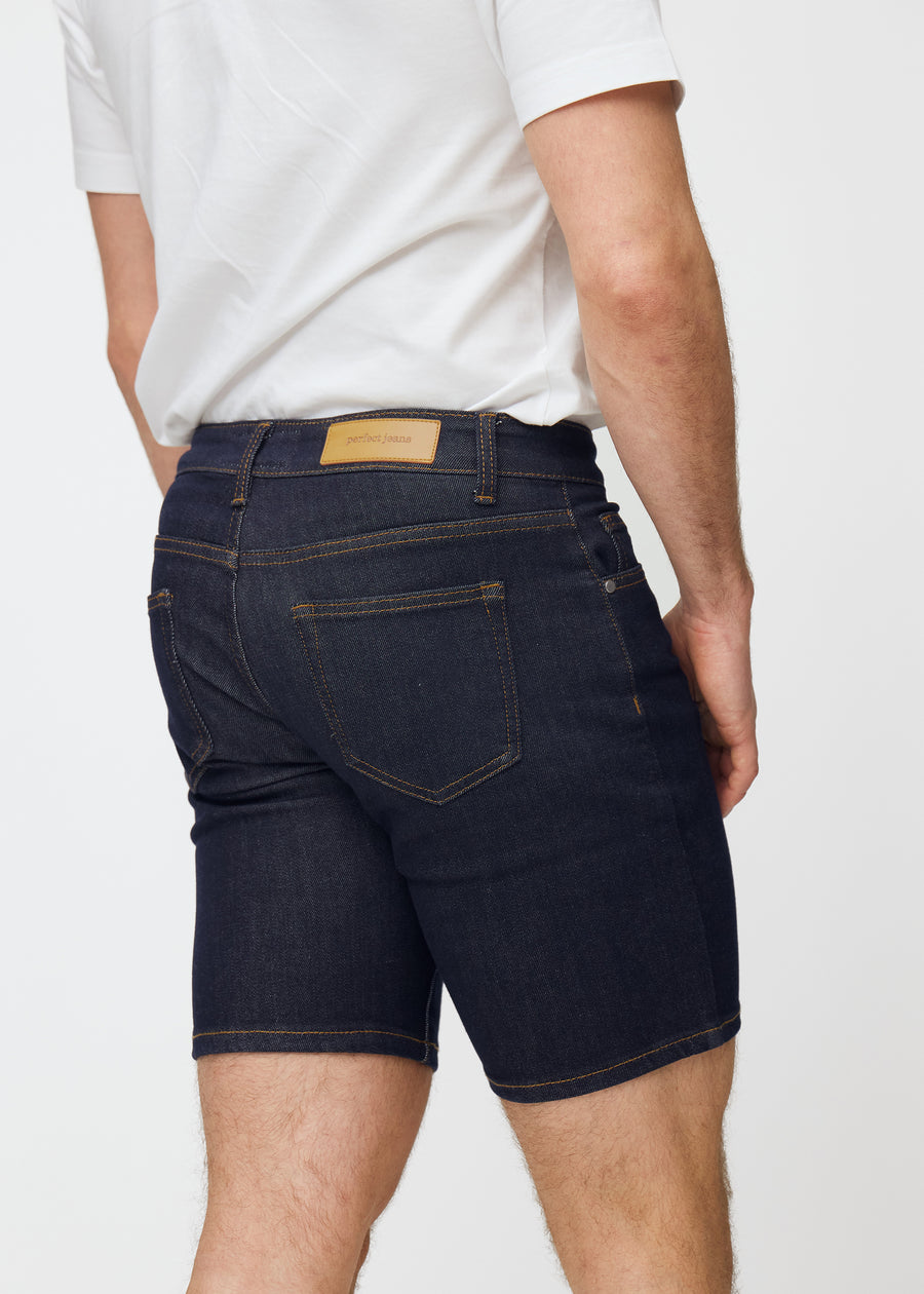 Deep dark blue denim shorts for men in the colour Midnights seen from the back in close-up to show fit and details.