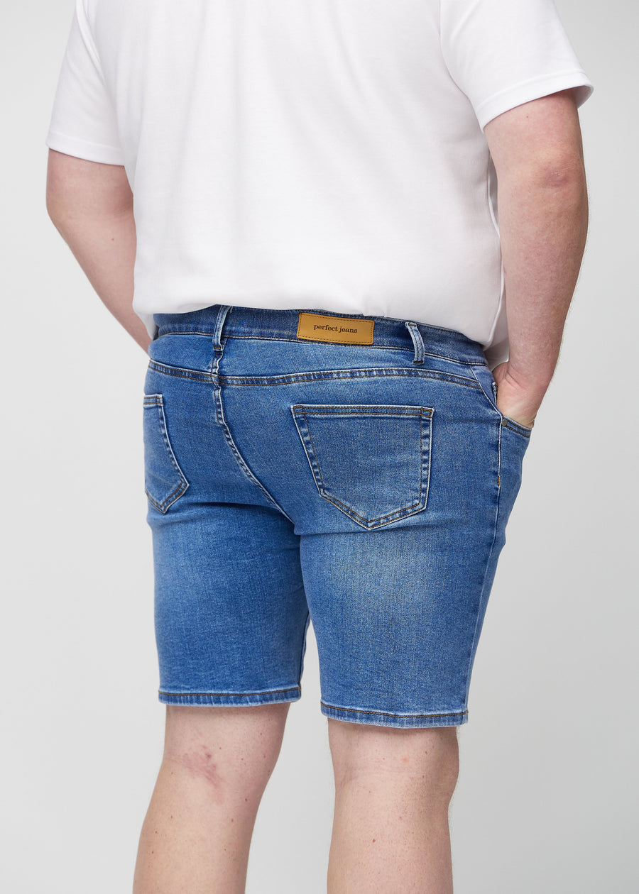 Denim middle-slim shorts seen from the back close up on a plus-size model to show details.