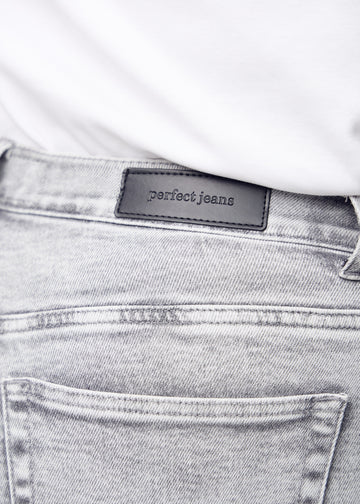 Baglommen på lysegrå denim set tæt på – tydeligt logo og tekstur vist på en plus-size model.