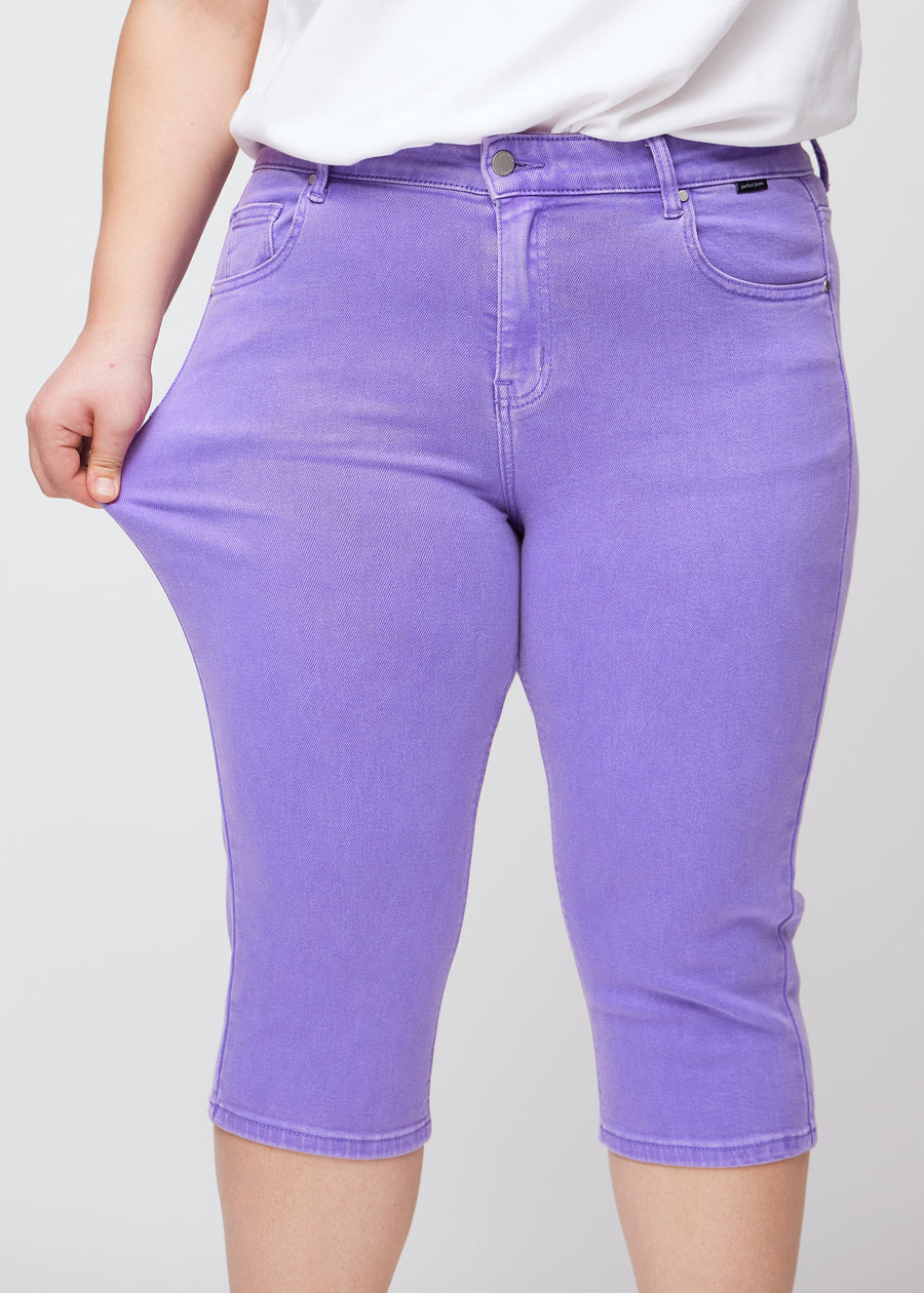 Plus-size model viser stretch ved at trække i caprisene ved låret – fokus på komfort og fleksibilitet.