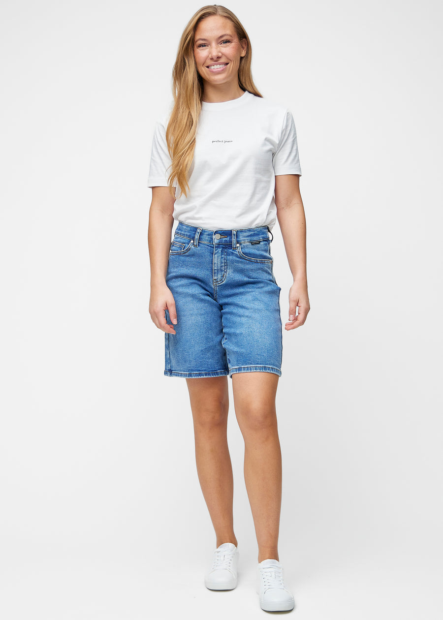 Model viser løse, klassisk blå denim shorts i farven Rivers i bevægelse og demonstrerer pasform og materiale.