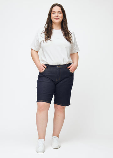 Plus-size model viser dyb mørkeblå denim shorts til kvinder i farven Midnights med regular pasform i bevægelse.